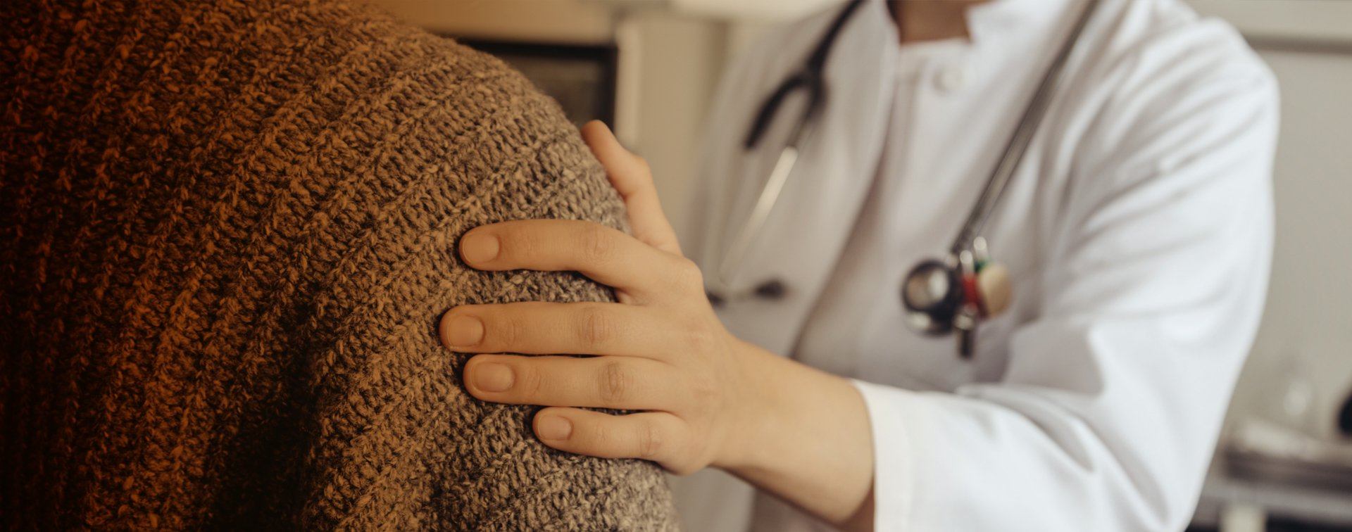 Läkare håller en hand på en patients axel.