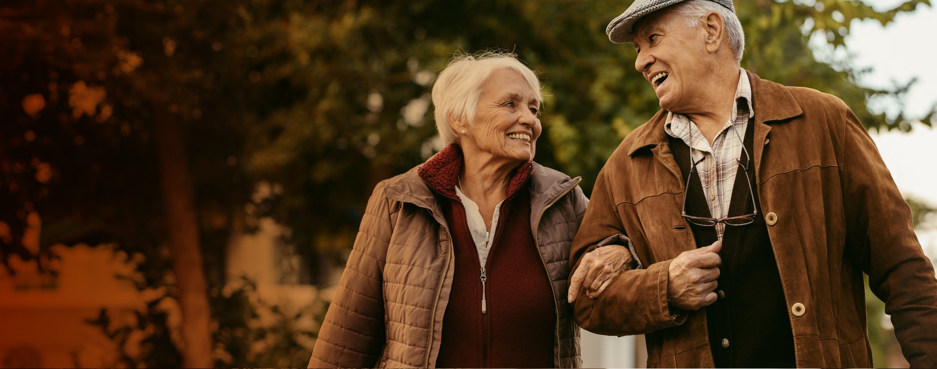 Ett äldre par som promenerar tillsammans utomhus.