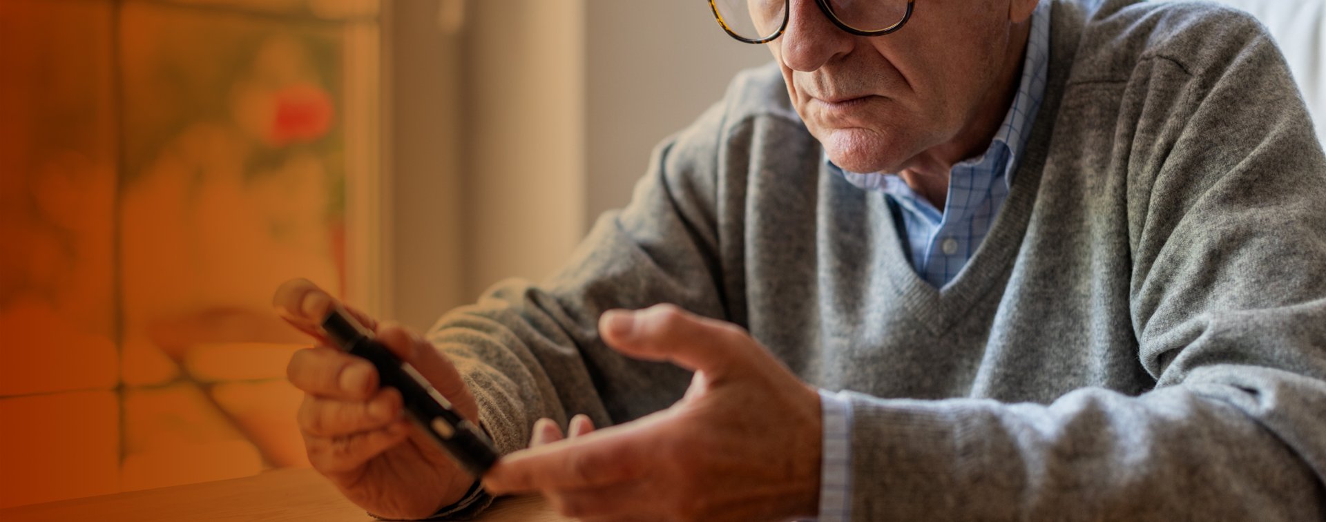 Äldre man som använder en blodsockermätare.