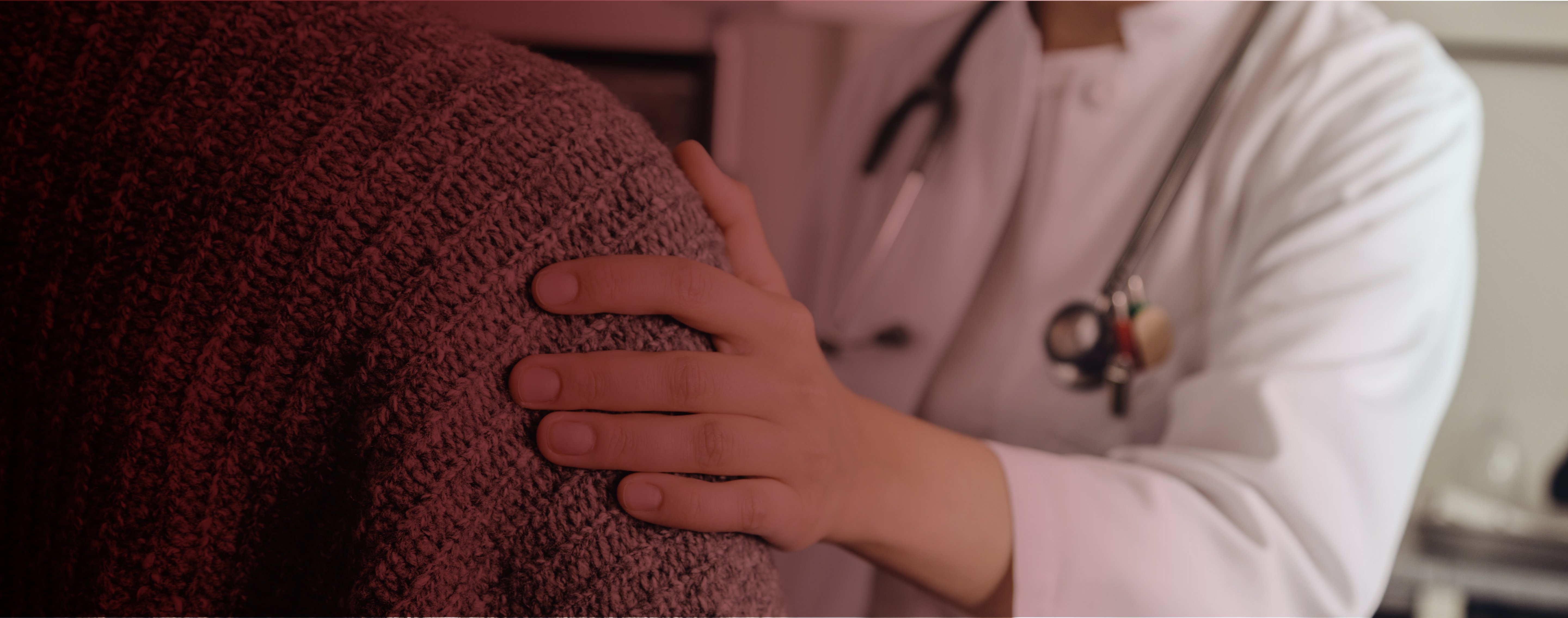 Läkare håller en hand på en patients axel.